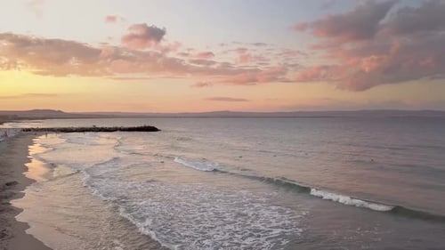 Aerial view of a sea surface with blue water waves under sunset sky.
