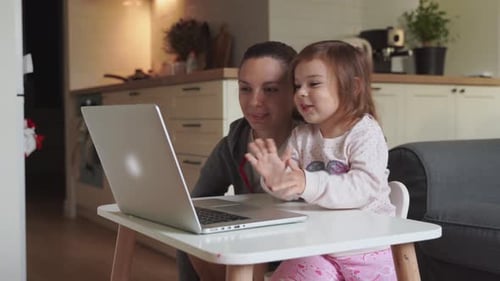 Mother and Child Girl Sitting at Home Ad Watching School Video on Laptop. Distant Education