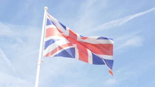 UK Flag Fluttering in the Breeze Against Blue Sky