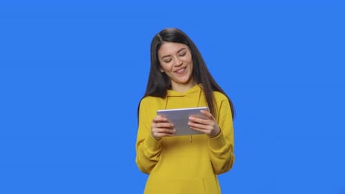 Young Woman Using Tablet on Blue Background