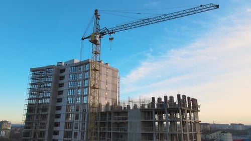 Vista aérea de una grúa de torre alta y un edificio de apartamentos residenciales en construcción al atardecer