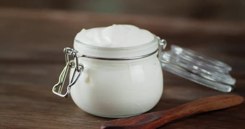 La crème sure dans un bocal en verre sur la table tourne lentement.