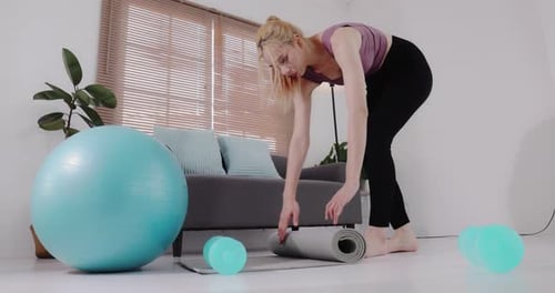 Woman Unrolls Yoga Mat for Home Workout