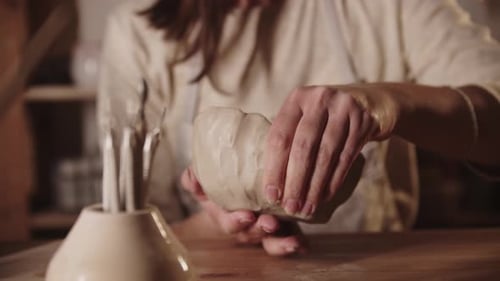 Woman Shapes Clay on Wooden Pottery Table