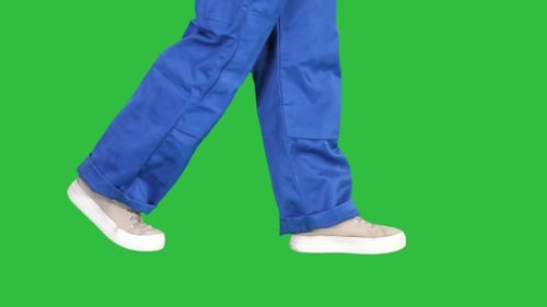 Legs of woman construction worker walking on a Green Screen