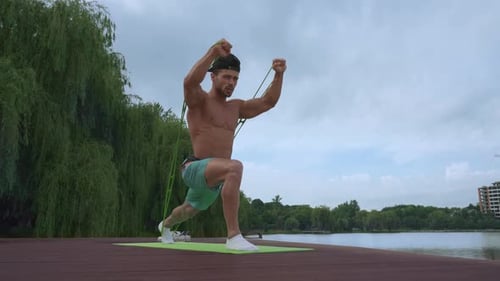 Powerful Male Athlete Doing Exercises for Arms Near Lake