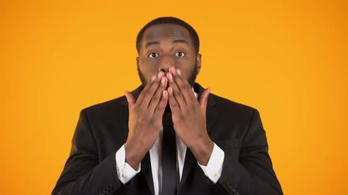 Man in Suit Expressing Shock on Orange Background