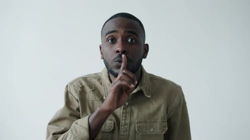 Portrait of Serious Young AfroAmerican Man Asking for Silence Touching Lips with Finger