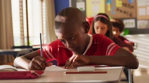 Focused Student Writing in Classroom at School Desk