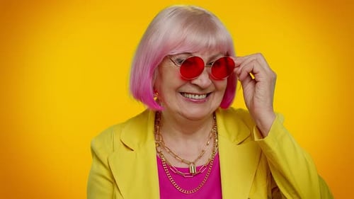 Smiling Senior Woman Puts on Red Glasses