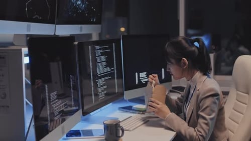 Female Programmer Eating at Desk at Night