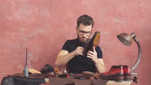 Craftsman Inspecting Handcrafted Leather Shoe in Workshop