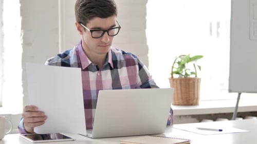 Young Adult Working at Laptop in Modern Office