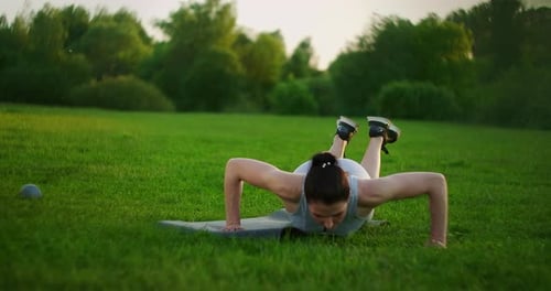 Rare View of Sexy Girl Is Pushing Up From in a Park at Sunset. Workout. Work on a Beautiful Body in