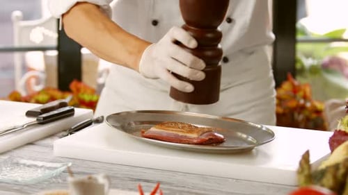 Chef Adds Fresh Pepper to Meat in Kitchen