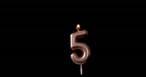 Burning Number Five Candle Against Black Background