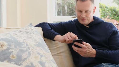 Man Relaxing on Couch Using a Smartphone