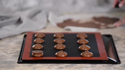 Woman Hands Assembling Chocolate Macarons on Tray
