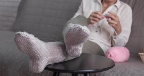 Woman Knitting with Needles on Couch Indoors