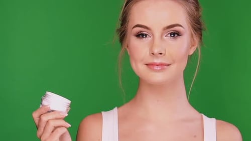 Woman Holds Cosmetic Cream Container Against Green Screen