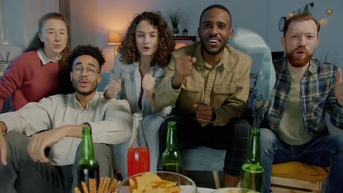 Portrait of Enthusiastic Sports Fans Cheering Watching Game on TV and Looking at Camera at Home at