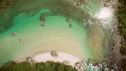 Aerial view of a group doing rafting with clean water and rocks on bottom.