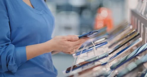 Close-up of the Hand of a Woman Holding a New Smartphone in Her Hands and Choosing To Buy the Best