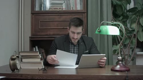 Young Professor Having a Video Call Via Tablet To Discuss Paper Written By His Student