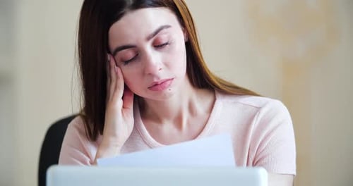 Stressed Woman Working at Laptop with Document