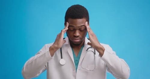 Professional Medical Doctor Suffering From Acute Migraine Attack, Blue Studio Background