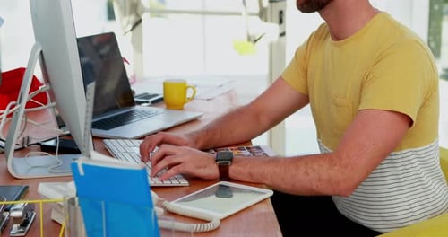 Man Typing at Computer in Office, Smiles