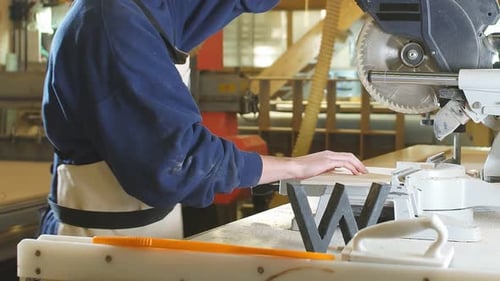 Young Adult Using Miter Saw in Workshop