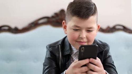 Boy Smiling Using Mobile Phone Indoors