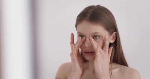 Young Woman Applies Lotion to Her Face