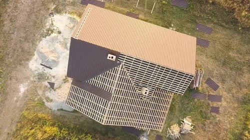 Aerial View of Unfinished House with Wooden Roof Structure Covered with Metal Tile Sheets Under
