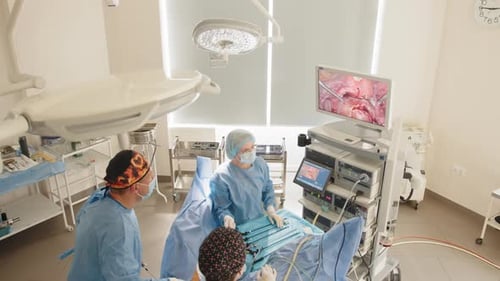 Surgeons Team Looks at Monitors While Preforming Operation in Hospital Operating