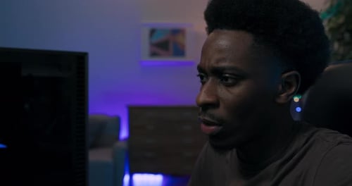 Close Up Shot of Young Man's Face Professional Gamer Sits Comfortably in Chair Bent Over Computer