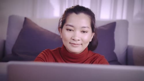 Young Woman Uses Laptop While Sitting on Couch