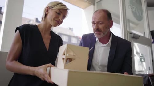 Architect explaining model to customer in cafe
