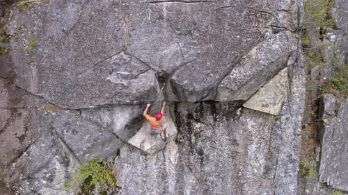 Aerial Of Professional Rock Climber On Dangerous Mountain Cliff High Above Forest Canopy