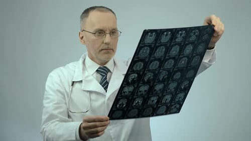 Neurocirujano revisando la imagen cerebral por resonancia magnética, mirando a la cámara, servicios de atención médica