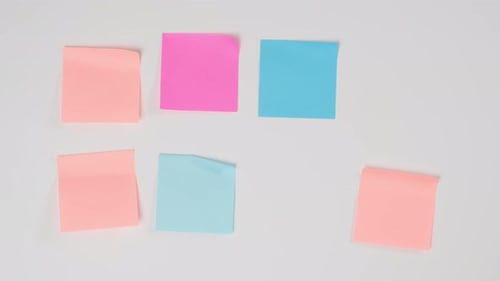 female hand gluing blank square multicolored stickers on white board