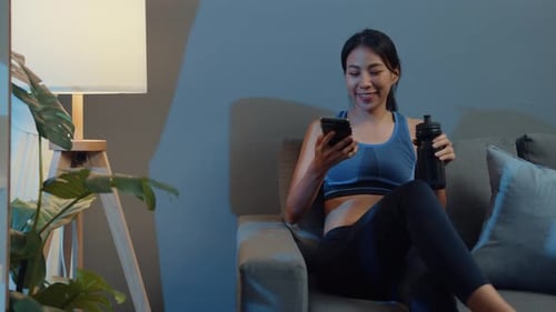 Woman Relaxing on Couch with Phone and Water Bottle