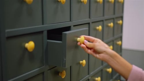 A Woman Hand Searching Cards in Old Wooden Card Catalogue