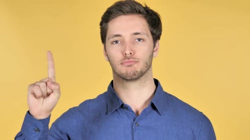 Man Raising Finger Indicates No on Yellow Background