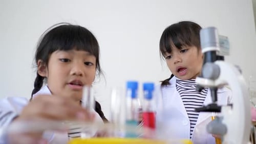 Girls Doing Science Experiment with Beakers and Microscope