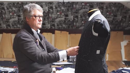 Outstanding Mature Tailor Working with Cut Patterns at Sewing Workshop in Late Evening.