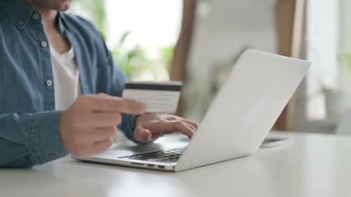 Person Using Credit Card and Laptop at Home