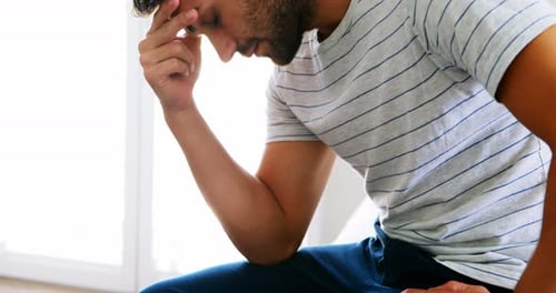 Man Contemplating and Holding Forehead in Home
