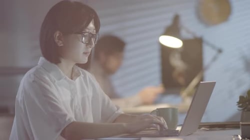 Femme d'affaires asiatique travaillant dans un bureau éclairé par une lampe